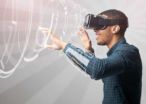 A person wearing a VR headset engages with virtual graphics, exemplifying cutting-edge technology solutions, while standing in profile. A person wearing a VR headset engages with virtual graphics, exemplifying cutting-edge technology solutions, while standing in profile.
